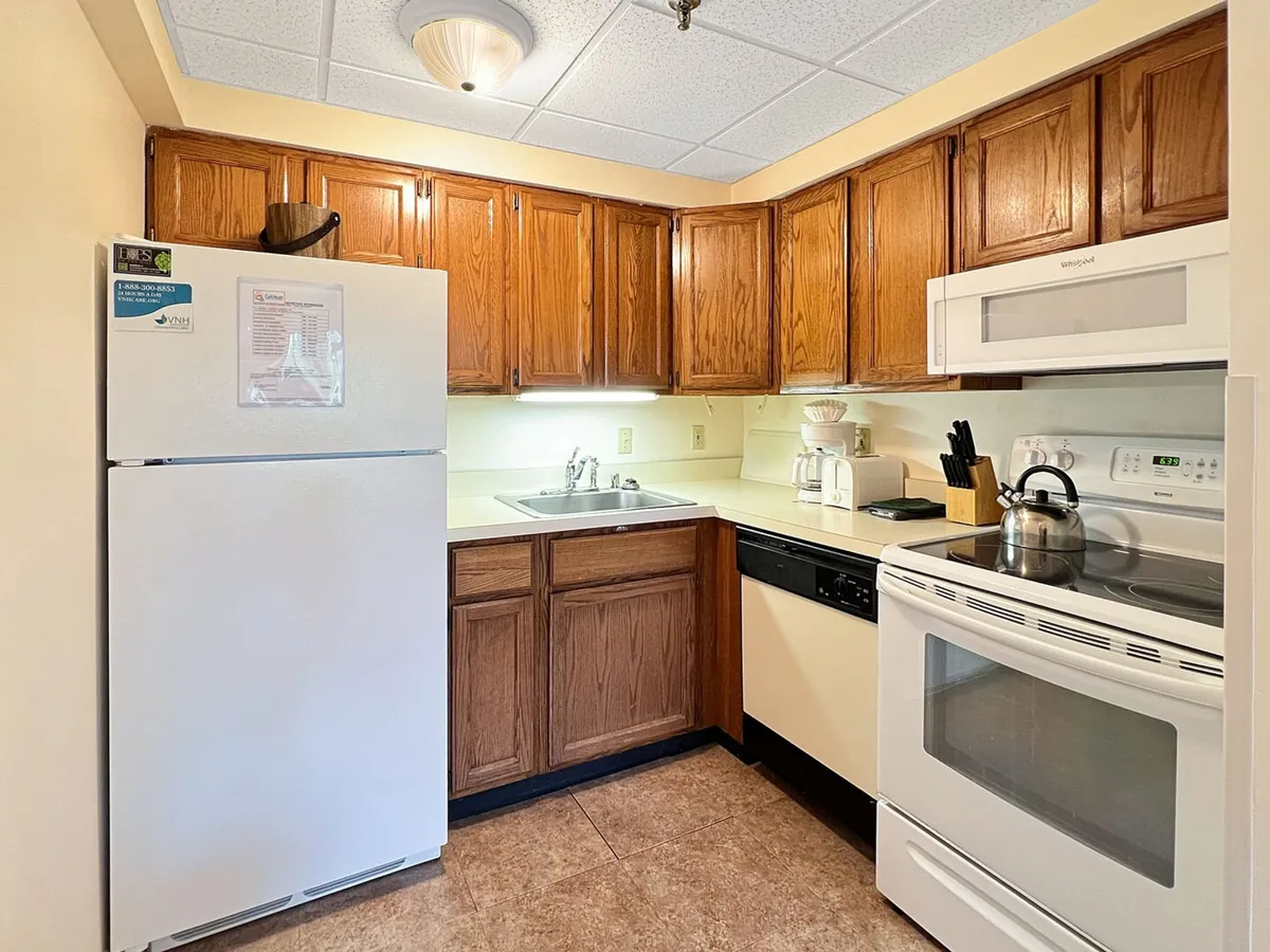 A homey kitchen with white refrigerator, wooden cabinets, and stainless steel appliances. Spacious countertops invite meal prep and baking, while the overall setup suggests a welcoming space for culinary creativity and family gatherings.