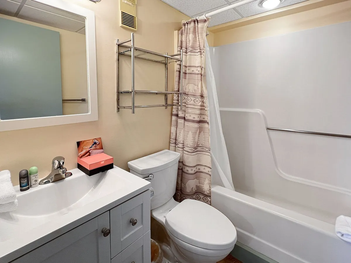 The image displays a newly updated bathroom with a modern vanity sink, mirror, fresh-looking shower curtain, and calming lighting. The setting is clean, stylish, and designed for relaxation and daily comfort.