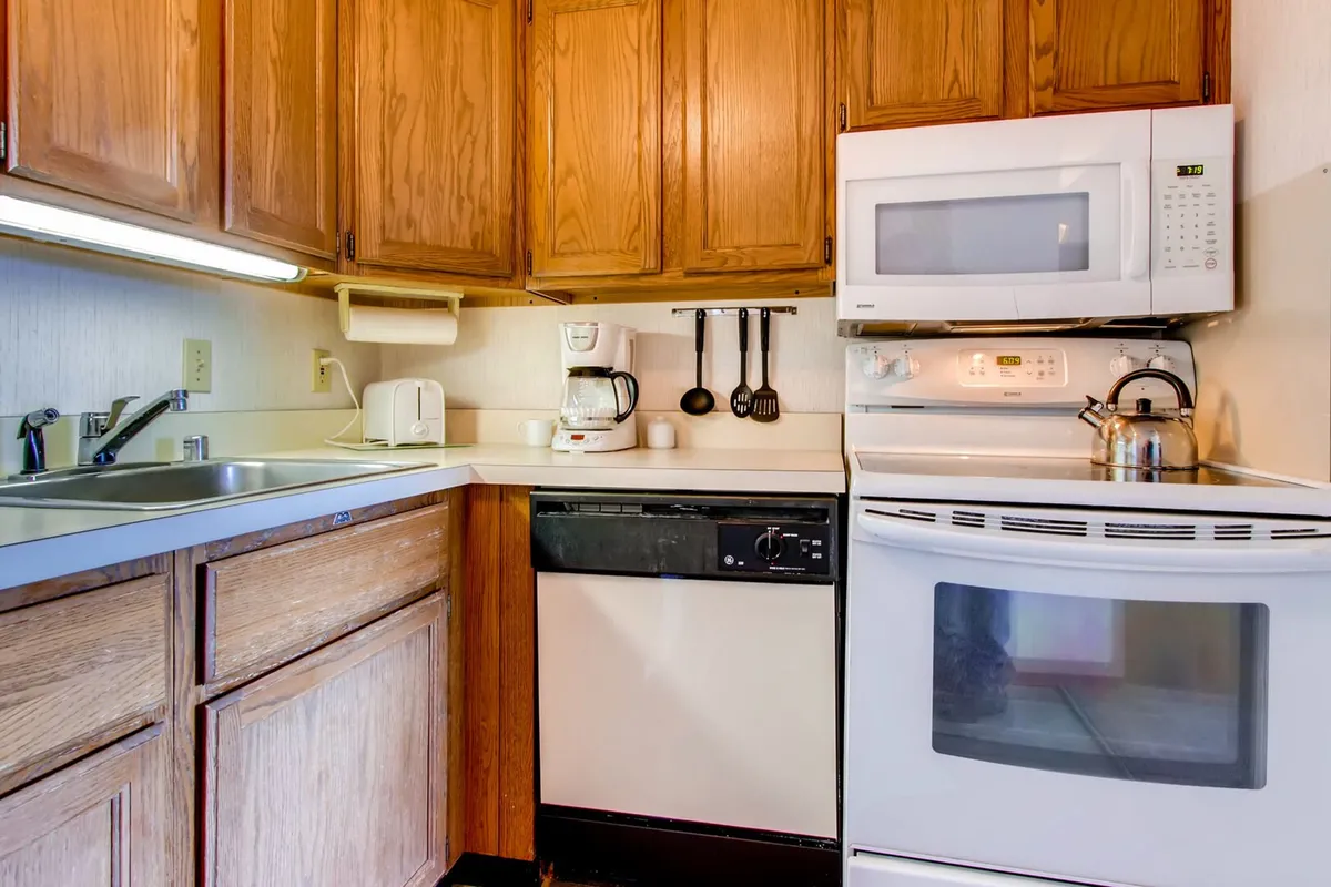 A comfortable, homey kitchen with wooden cabinets, visible appliances, and generous countertop space. The setup suggests easy conversation and collaborative cooking, echoing the memories created while preparing and sharing food.