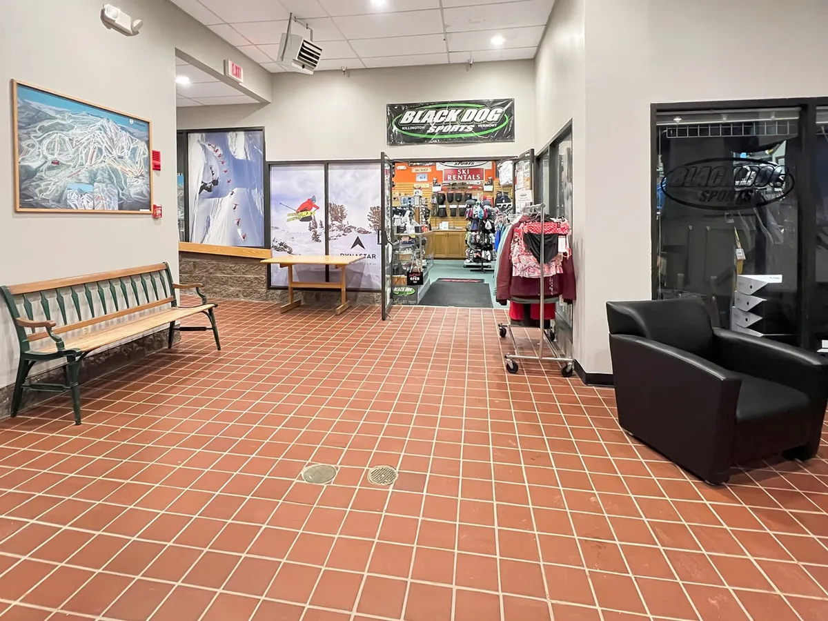 The inviting entrance to Black Dog Sports, with benches for resting and displays filled with ski and snowboard gear. The shop is integrated into the resort, highlighting the ease of gearing up right on-site.